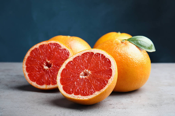 Fresh tasty grapefruits on table against color background - Foto, Imagem