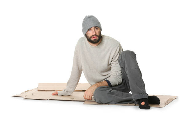 Poor homeless man sitting on cardboard, white background - Foto, afbeelding
