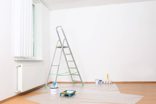 Stepladder and painting tools near wall in empty room - Foto, Imagem