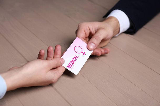 Man giving medical business card to girl at table, closeup. Women's health service - Photo, image