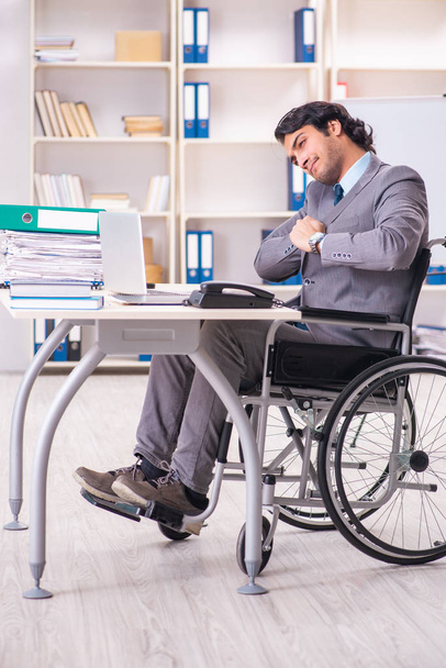 Молодий красивий працівник в інвалідному візку в офісі
  - Фото, зображення