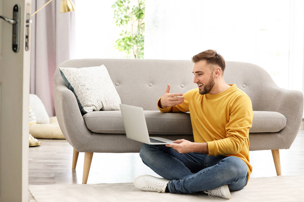 Young man using video chat on laptop in living room - Φωτογραφία, εικόνα