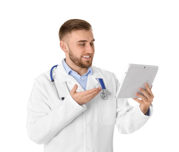 Male doctor using video chat on tablet against white background - Valokuva, kuva