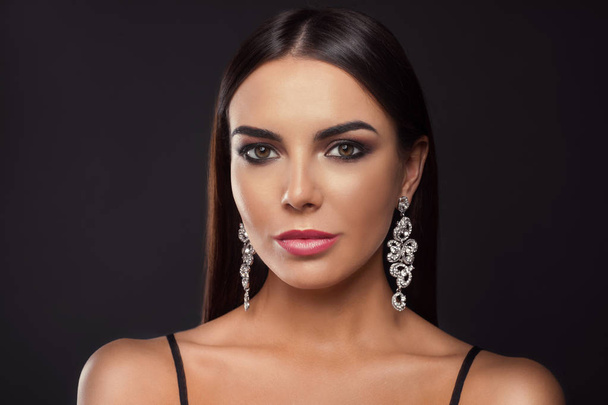 Beautiful young woman with elegant jewelry on dark background - Fotó, kép
