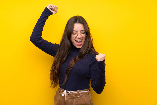 Adolescente sur un mur jaune isolé célébrant une victoire
 - Photo, image