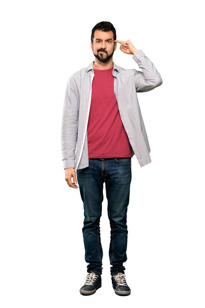 Full-length shot of Handsome man with beard making the gesture of madness putting finger on the head over isolated white background - Foto, imagen