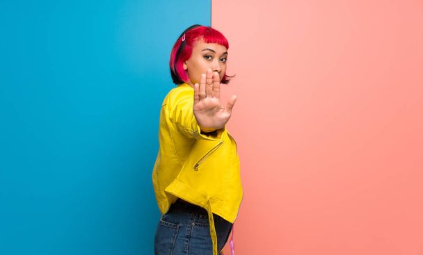 Jonge vrouw met gele jas maken stop gebaar voor teleurgesteld met een mening - Foto, afbeelding
