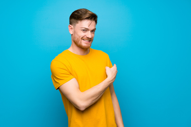 Redhead man over blue wall pointing back - Photo, Image