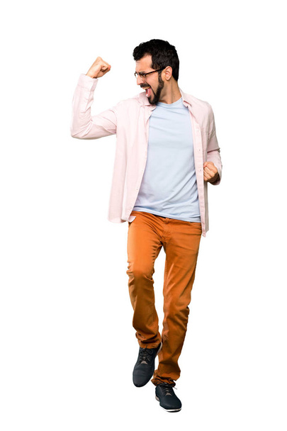 İzole beyaz arka plan üzerinde bir zafer kutluyor sakallı yakışıklı adam tam uzunlukta atış - Fotoğraf, Görsel