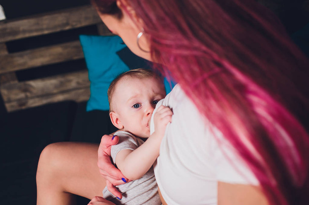 Mother breastfeeding baby in her arms at home. Beautiful mom Red hair breast feeding her newborn child. Young woman nursing and feeding baby. Concept of lactation infant. - Photo, image