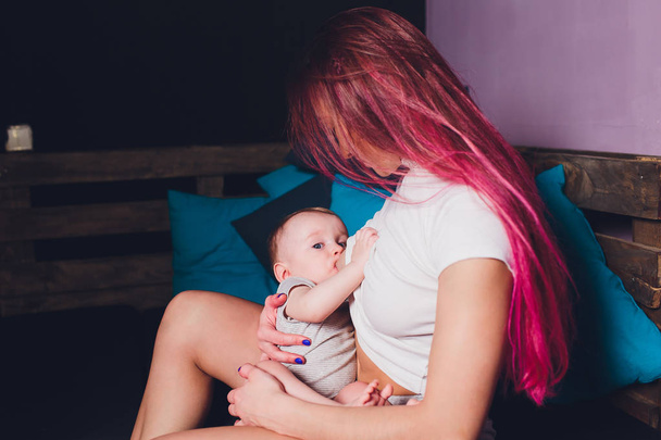 Mother breastfeeding baby in her arms at home. Beautiful mom Red hair breast feeding her newborn child. Young woman nursing and feeding baby. Concept of lactation infant. - Foto, Bild