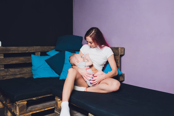 Mother breastfeeding baby in her arms at home. Beautiful mom Red hair breast feeding her newborn child. Young woman nursing and feeding baby. Concept of lactation infant. - Foto, Imagen