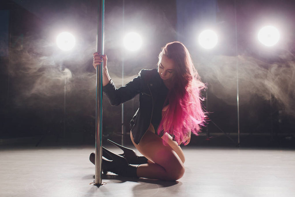 beautiful pole dancer in leather jacket on pylon. - Foto, afbeelding