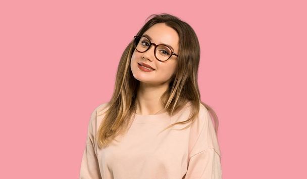 Teenager girl with pink sweater with glasses and happy over isolated pink background - Foto, imagen