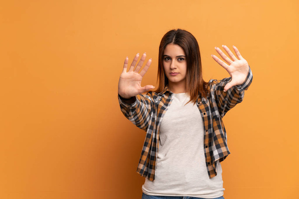 Молодая женщина за коричневой стеной делает остановку жест и разочарование
 - Фото, изображение