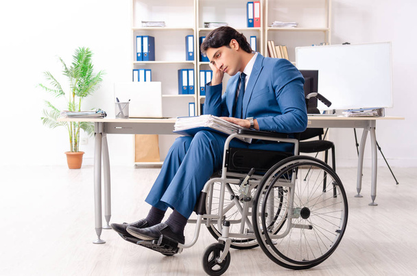 Мужчина в инвалидной коляске работает в офисе
  - Фото, изображение