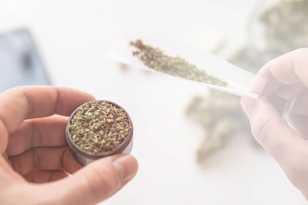 Grinder zur Hand und entrollte Joint Weed und Cannabis Marihuana von oben Ansicht Licht Lecks Farbtöne - Foto, Bild