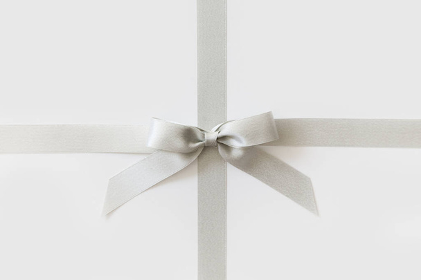 Silver ribbon with a bow as a gift on a white background - Fotó, kép