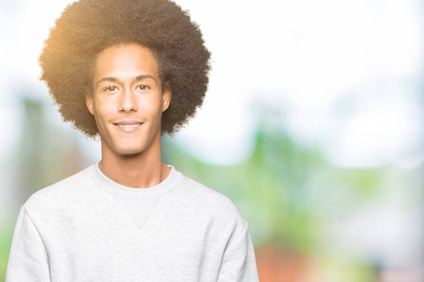 Young african american man with afro hair wearing sporty sweatshirt Hands together and fingers crossed smiling relaxed and cheerful. Success and optimistic - Photo, Image