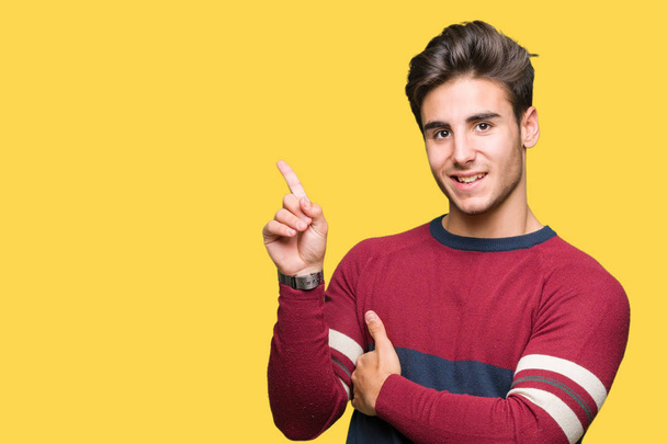 Young handsome man over isolated background with a big smile on face, pointing with hand and finger to the side looking at the camera. - Photo, Image