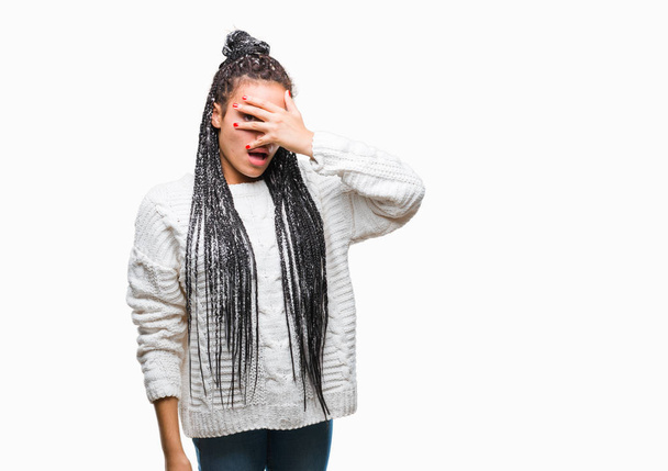 Νέος braided μαλλιών αφρικανικές αμερικανικές κορίτσι φορώντας πουλόβερ πάνω από απομονωμένες φόντο peeking σε κατάσταση σοκ που καλύπτουν το πρόσωπο και τα μάτια με το χέρι, κοιτάζοντας μέσα από τα δάχτυλα με αμηχανία έκφρασης. - Φωτογραφία, εικόνα