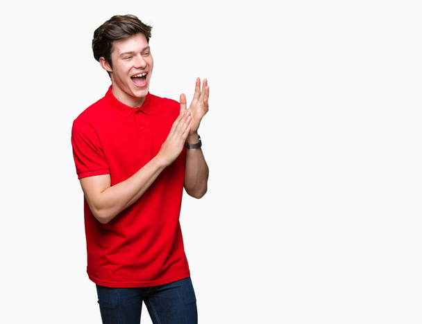 Młody przystojny mężczyzna noszenie czerwony t-shirt na na białym tle tła, oklaski i szczęśliwe i radosne, uśmiechnięte dumny ręce razem brawo - Zdjęcie, obraz