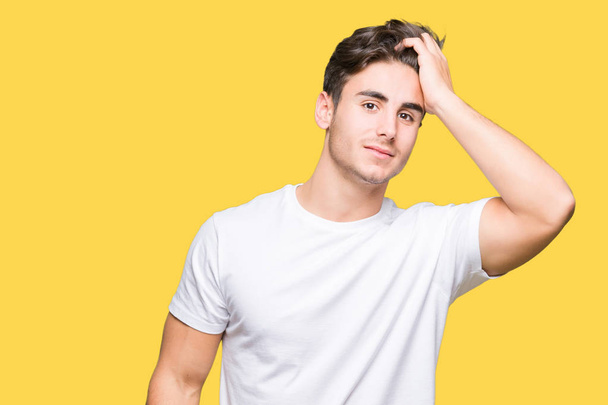 Young handsome man wearing white t-shirt over isolated background Smiling confident touching hair with hand up gesture, posing attractive - Foto, Bild