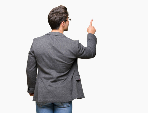 Young business man wearing glasses over isolated background Posing backwards pointing behind with finger hand - Photo, Image