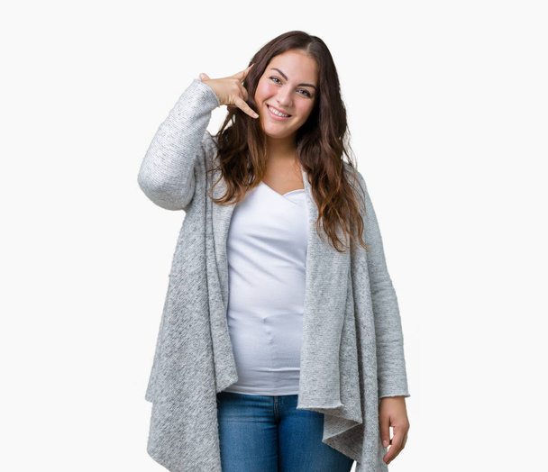 Beautiful plus size young woman wearing winter jacket over isolated background smiling doing phone gesture with hand and fingers like talking on the telephone. Communicating concepts. - Foto, afbeelding