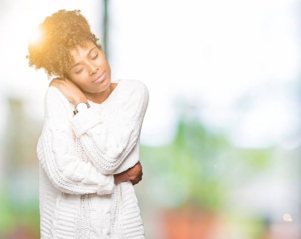 Beautiful young african american woman wearing winter sweater over isolated background Hugging oneself happy and positive, smiling confident. Self love and self care - Foto, Imagem