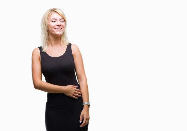 Young beautiful blonde attractive woman wearing elegant dress over isolated background looking away to side with smile on face, natural expression. Laughing confident. - Zdjęcie, obraz
