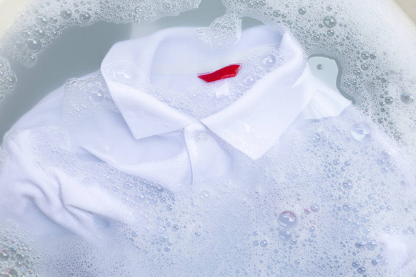Замочіть тканину перед пранням білої сорочки поло
.  - Фото, зображення