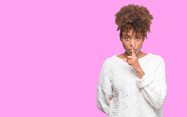 Krásná mladá africká americká žena nosí zimní svetr izolované pozadí chce být potichu s prstem na rtech. Mlčení a tajné koncept. - Fotografie, Obrázek