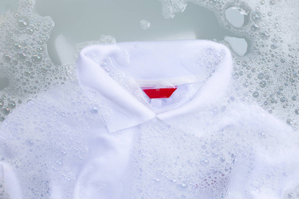 Замочіть тканину перед пранням білої сорочки поло
.  - Фото, зображення