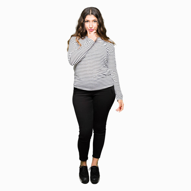 Young beautiful woman wearing stripes sweater looking confident at the camera with smile with crossed arms and hand raised on chin. Thinking positive. - Photo, image