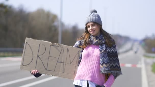 Młoda Ładna uśmiechnięta kobieta autostopem zatrzymanie samochodu z plakatem marzenie.  - Materiał filmowy, wideo