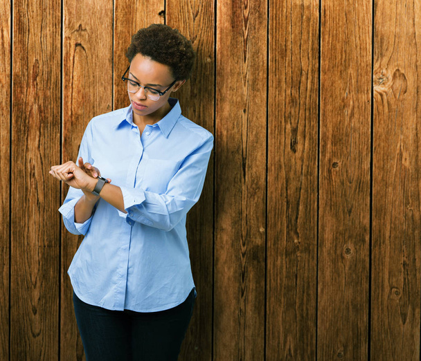 Giovane bella donna d'affari africana americana su sfondo isolato Controllare il tempo su orologio da polso, rilassato e sicuro
 - Foto, immagini