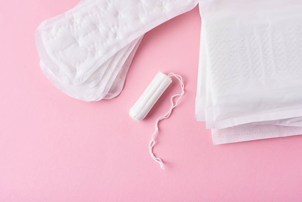 Almohadilla sanitaria y tampón menstrual sobre fondo rosa
 - Foto, Imagen