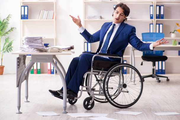 Молодий чоловік працівник в інвалідному візку працює в офісі
  - Фото, зображення