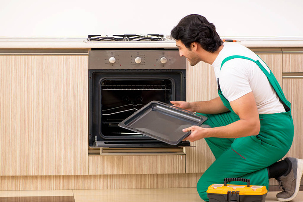 jonge aannemer reparatie oven in keuken  - Foto, afbeelding