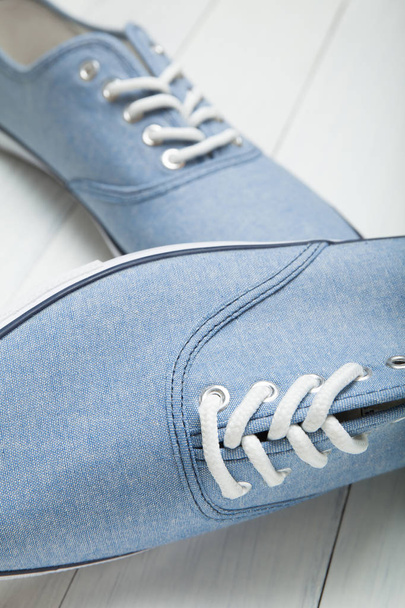 Fashionable casual blue sneakers with white laces on a blue back - Photo, Image