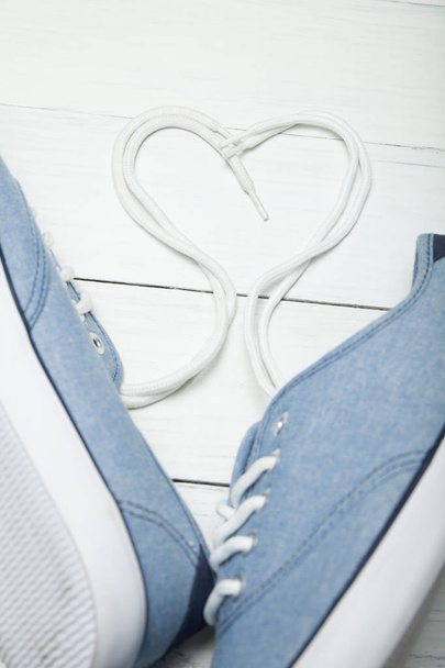 Comfortable casual shoes, heart made of white laces on a wooden  - Foto, Imagen
