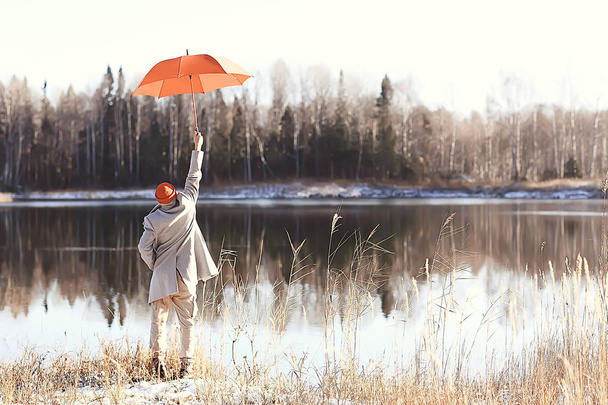 winter walk with an umbrella / man in a coat with an umbrella, walk against the backdrop of the winter landscape, winter view - Photo, Image