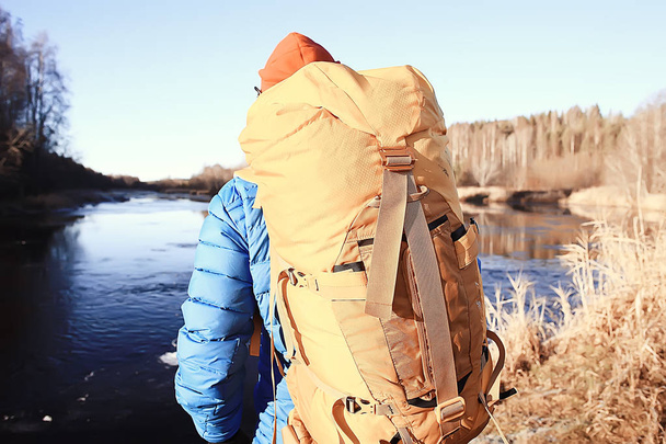 traveler with a backpack by the river / tourist guy on a northern hike, winter trip - Foto, immagini