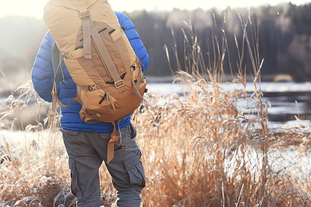 vista turística desde la espalda / un hombre con una mochila pasa por el bosque de invierno, vista de la salida
 - Foto, imagen