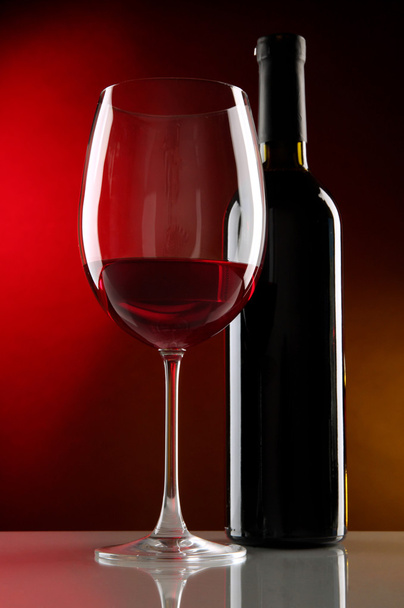 Glass of wine with bottle on bright red background - Foto, Bild
