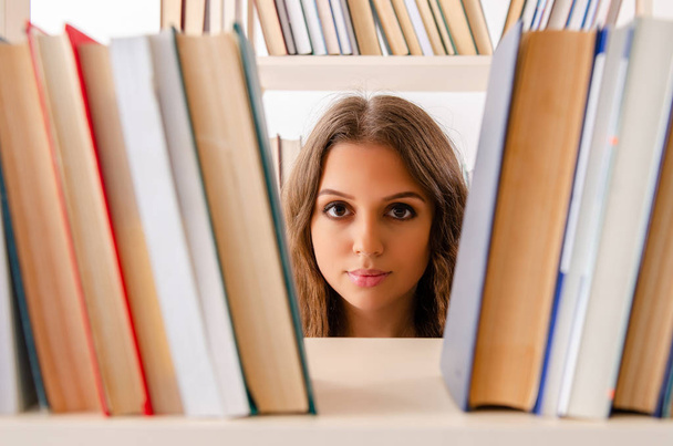 Jonge vrouwelijke student bereidt examens in de bibliotheek voor  - Foto, afbeelding