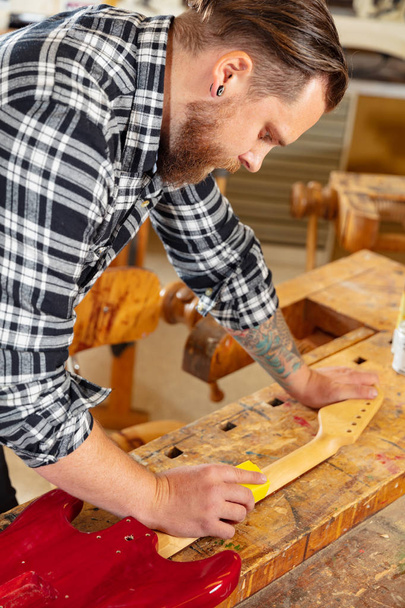 Zbliżenie: rzemieślnik szlifowanie szyi gitary w drewno o warsztatów - Zdjęcie, obraz