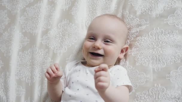 Boldog újszülött fiú feküdt a hátán, és mosolyog - Felvétel, videó
