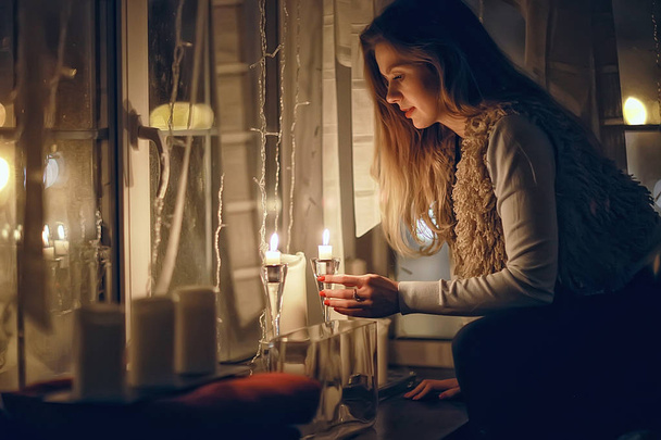 girl at the window dreams in winter evening / the romance of candle, the beautiful model in Christmas evening dreams - Foto, imagen